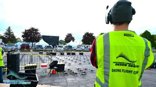 An image from before an NLDS drone show depicting a ground crewman overseeing the safety procedures for the drones. An image from before an NLDS drone show depicting a ground crewman overseeing the safety procedures for the drones.