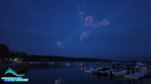 An image from our drone show at Lake Geneva showing a woman ziplining.