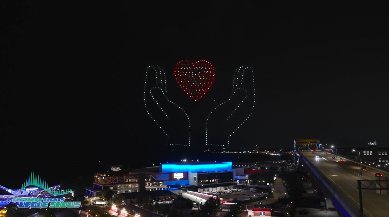 An image from a drone show by Northern Lights Drone Shows depicting two hands holding a large heart. An image from a drone show by Northern Lights Drone Shows depicting two hands holding a large heart.