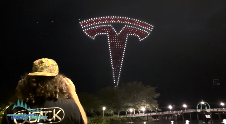 An image from the NLDS Tesla drone show featuring a spectator recording the show. An image from the NLDS Tesla drone show featuring a spectator recording the show.