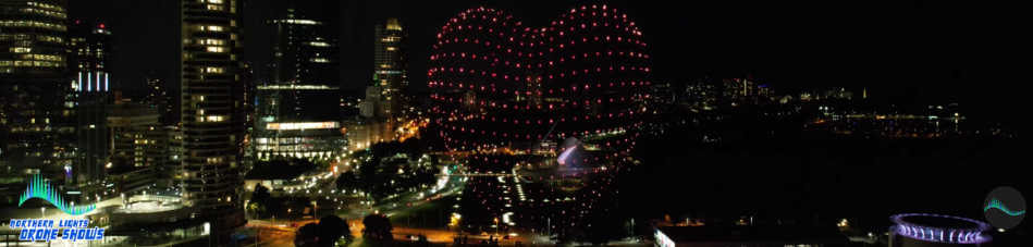 An image of a heart pulsating from an NLDS drone show over a city skyline.