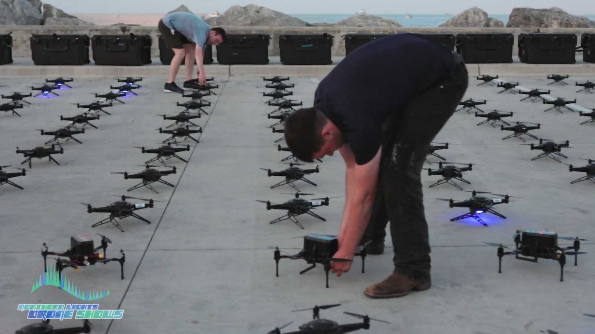 An image of two NLDS groundcrew members setting up a grid of drones prior to a launch.